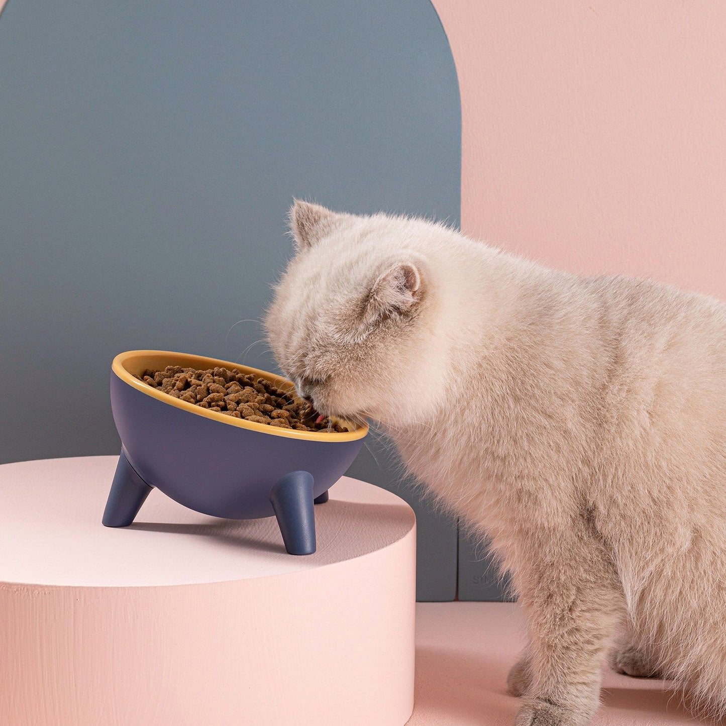 Two angled pet bowls in blue with glossy pink and yellow interiors shown together