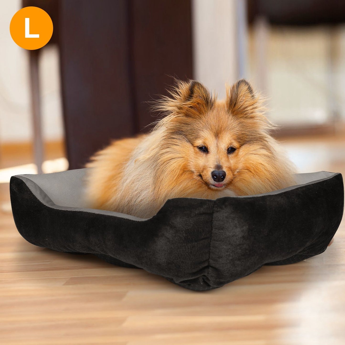Small fluffy dog resting in a black and gray plush rectangular pet bed on a wood floor