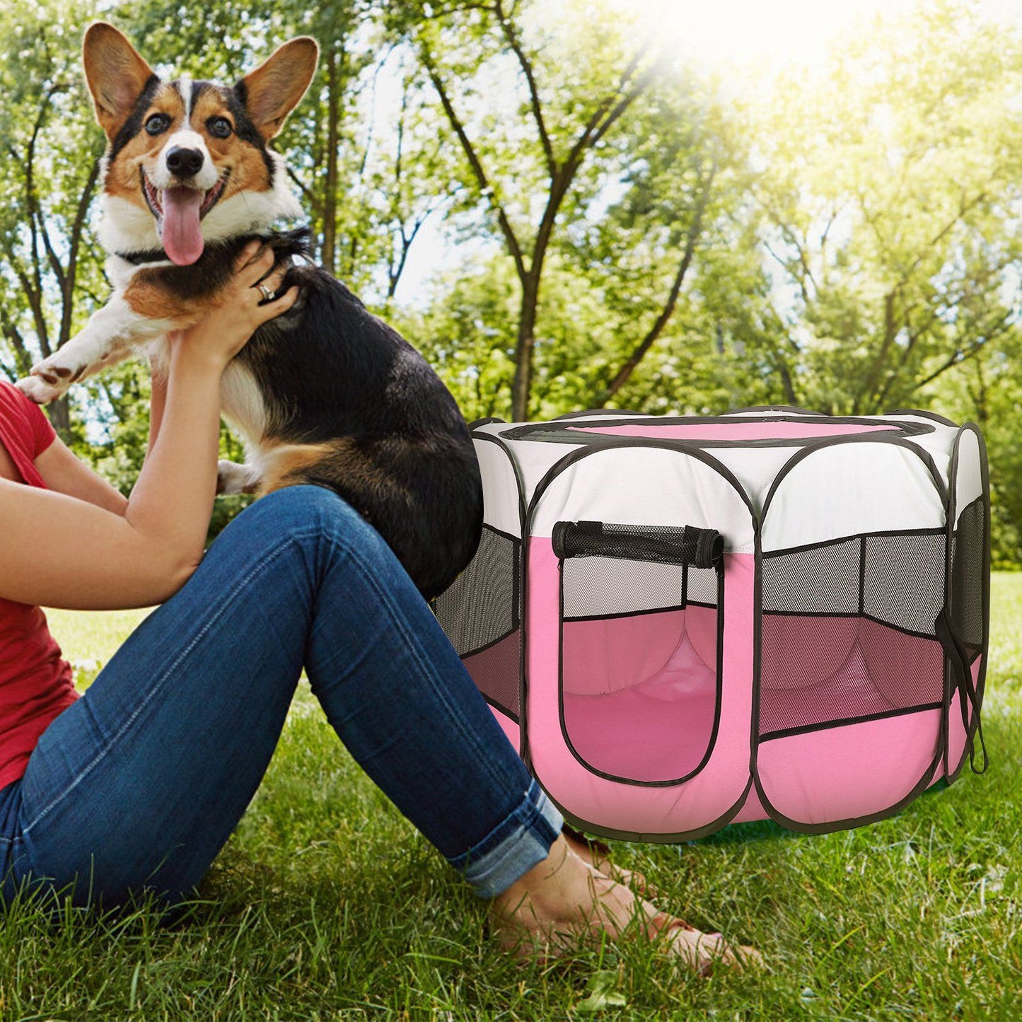 Pink playpen on grass at park beside person holding a dog, showing outdoor use