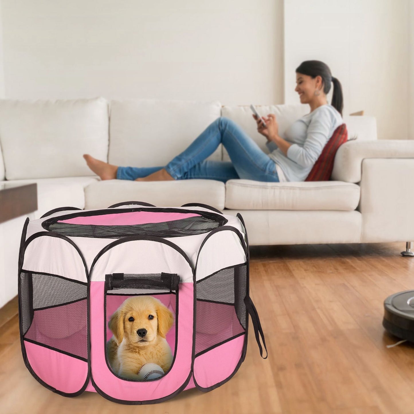 Pink playpen on floor in living room with small puppy inside and person on sofa