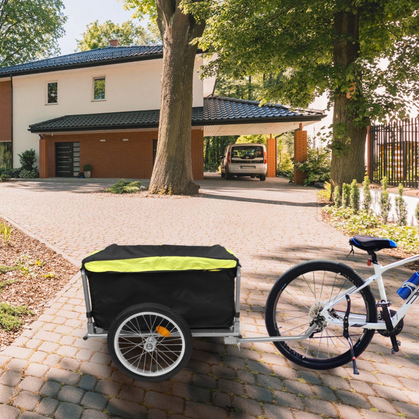 Bicycle with hitched cargo trailer parked on a driveway in front of a house