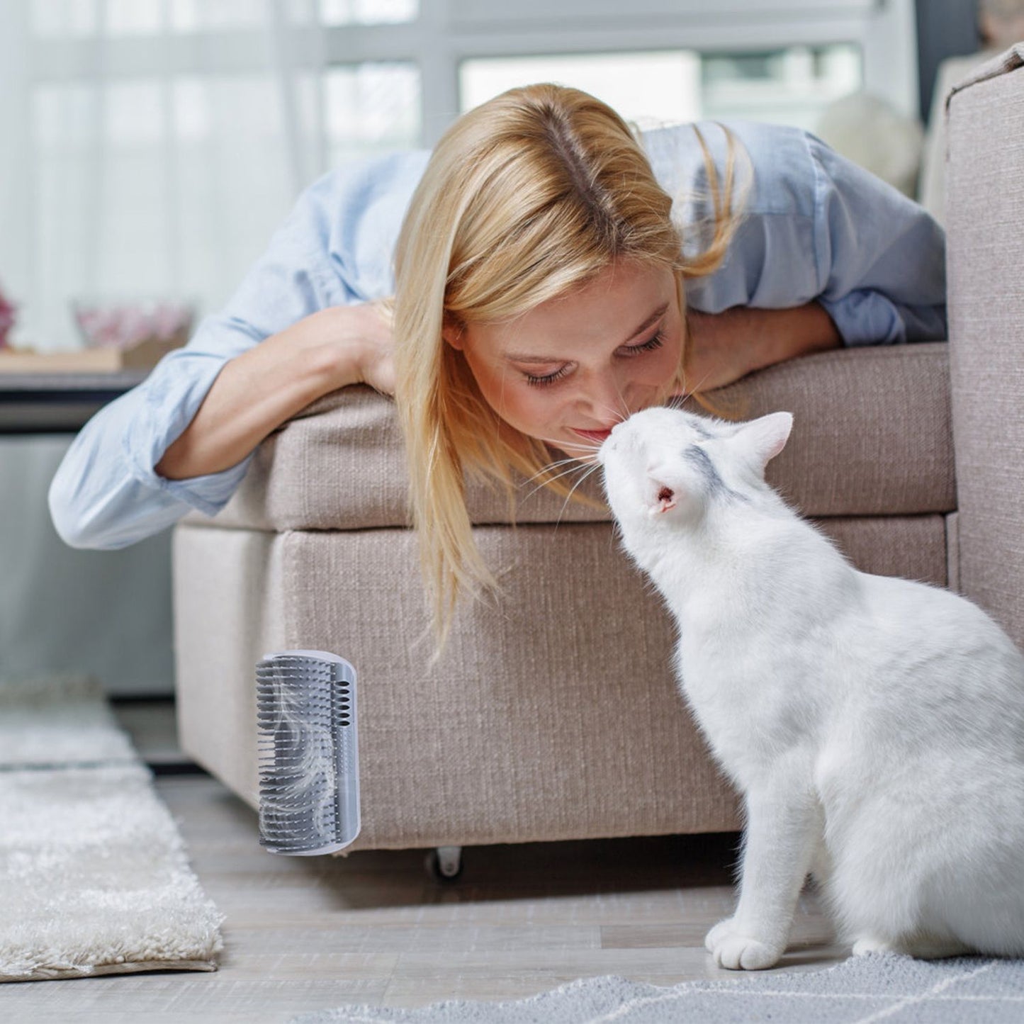 White cat near a grey mounted groomer attached to the side of a sofa