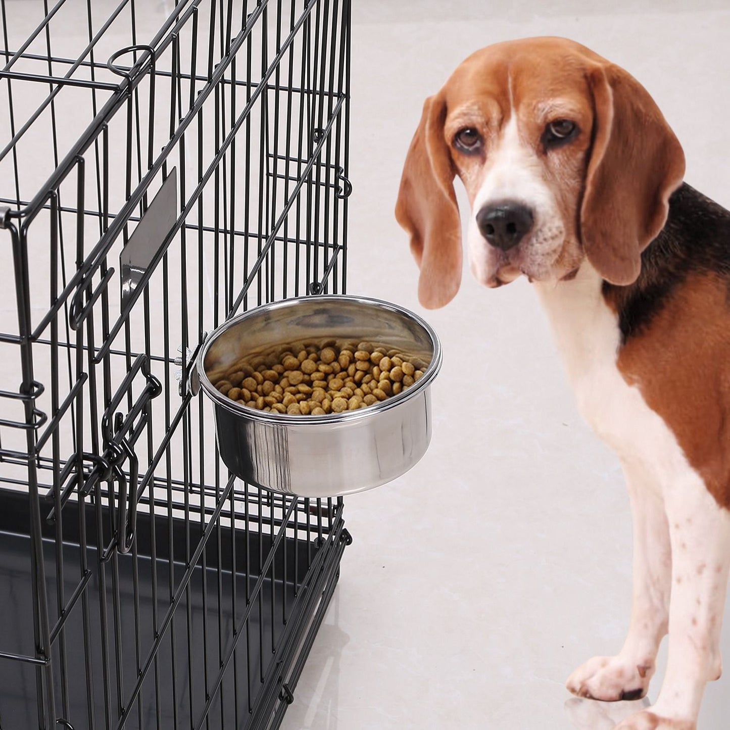 Hanging stainless steel bowl clamped to a wire pet crate filled with kibble