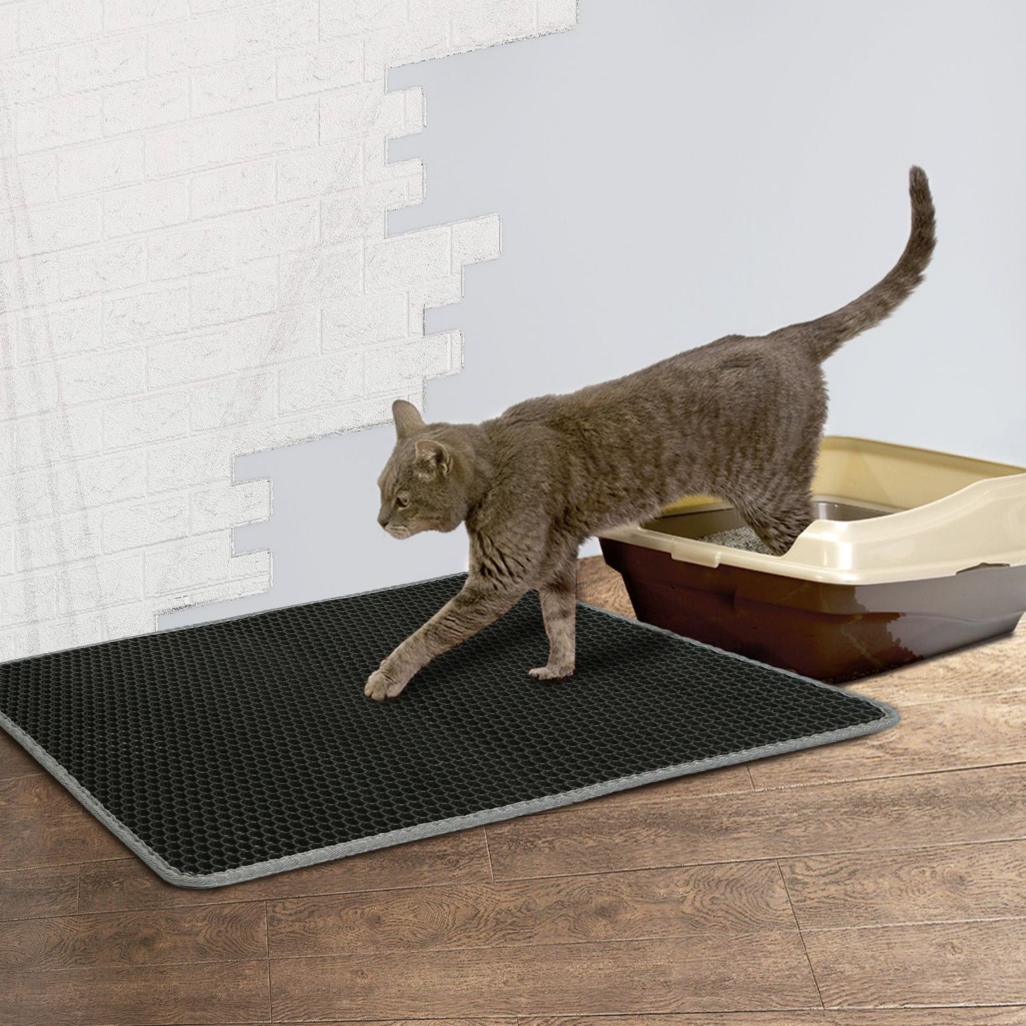 cat exiting open litter tray onto black honeycomb mat on hardwood floor to contain scattered litter