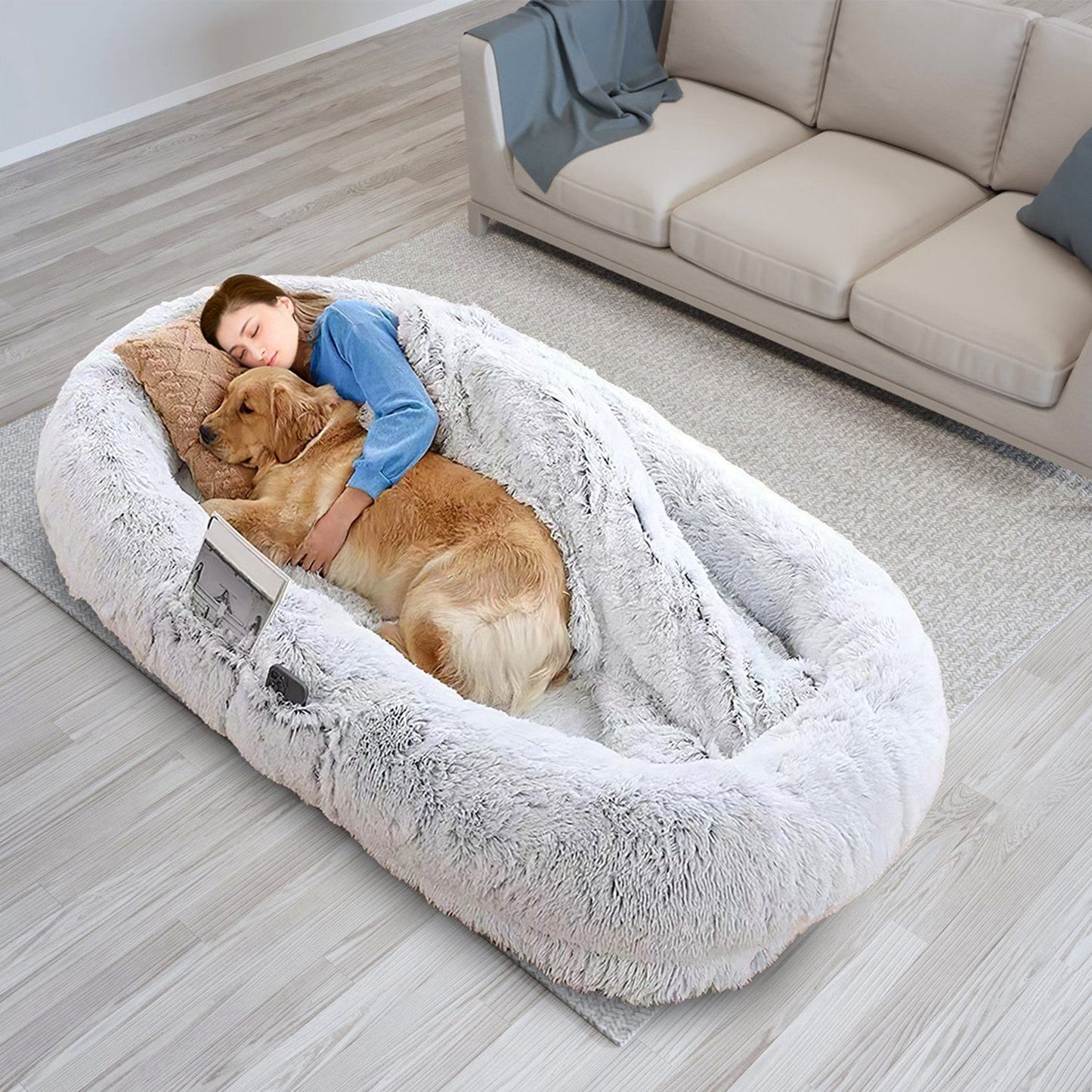 Top-down living room view of large plush bed on rug with person and dog cuddling