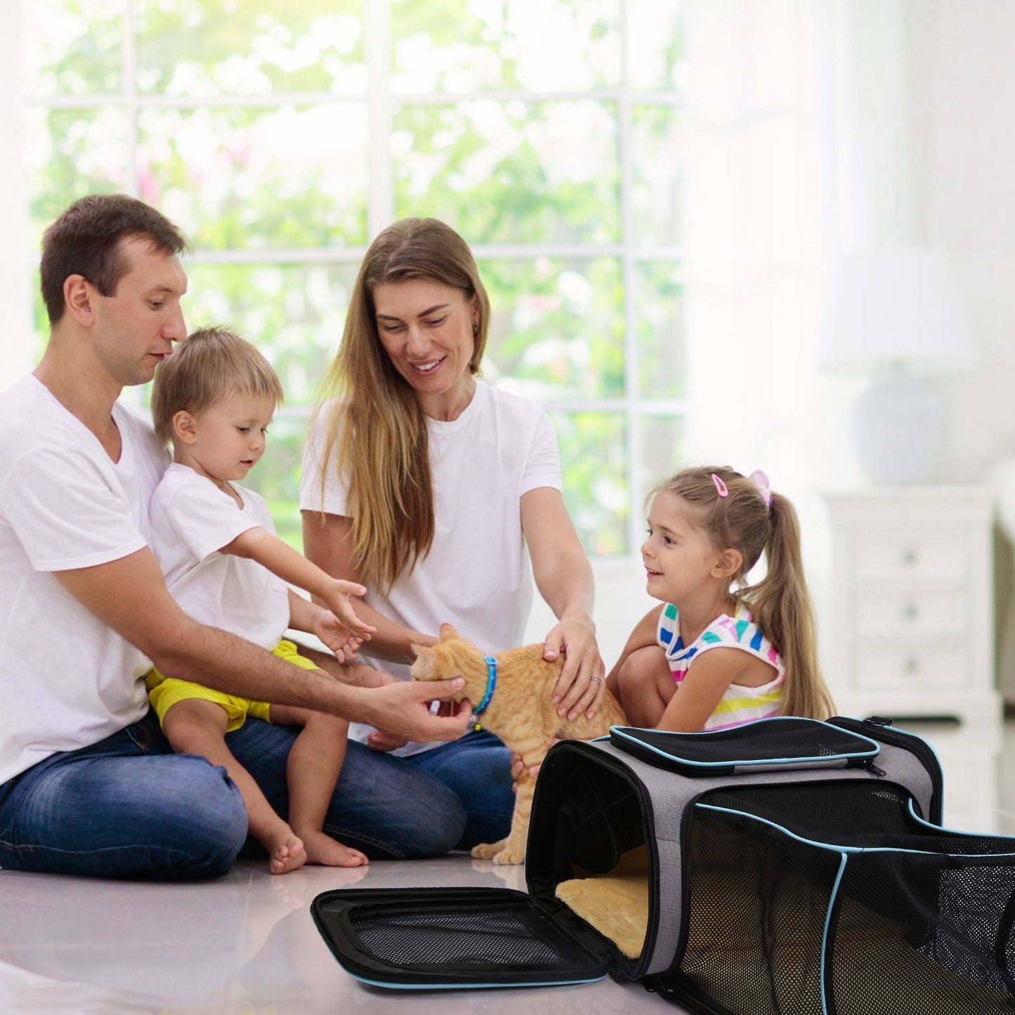 Family sitting on the floor petting a cat with the expandable carrier and side mesh extension open nearby