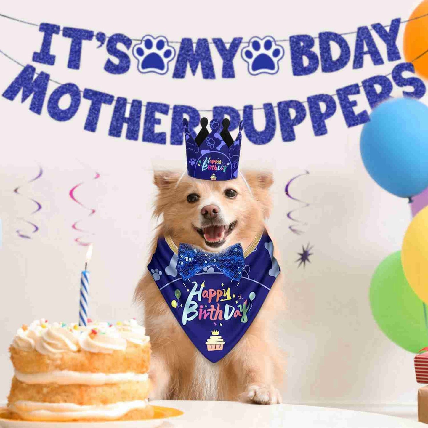 Golden dog wearing blue birthday bandana and crown with cake and festive banner in background