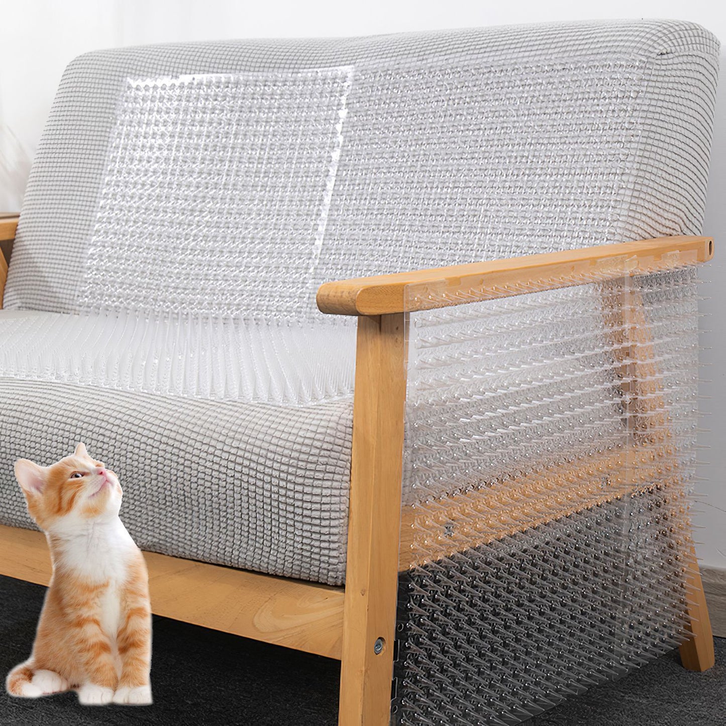 Transparent spiked mats placed over a sofa seat and armrest with a kitten nearby
