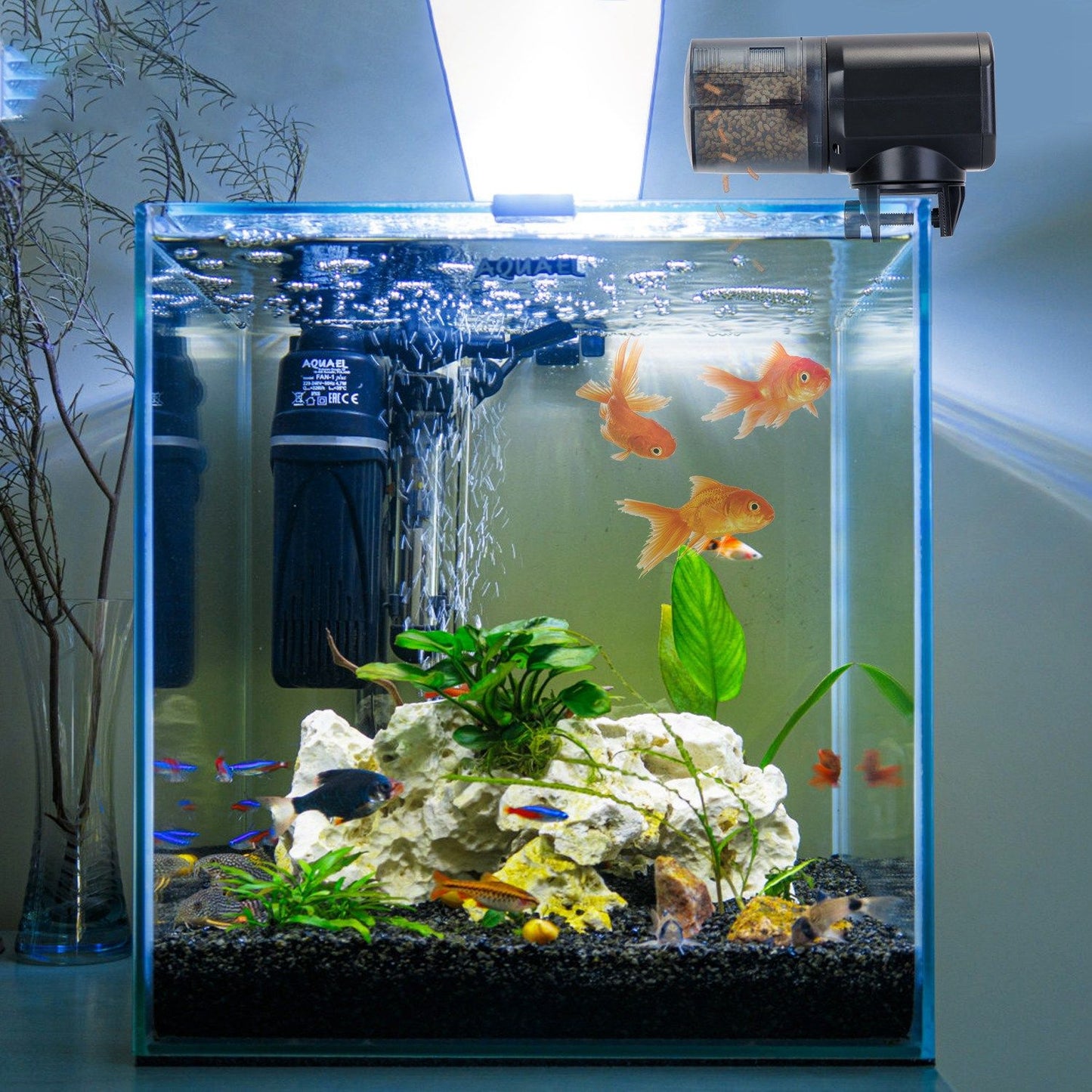Feeder mounted on illuminated aquarium rim dispensing pellets into water with fish nearby