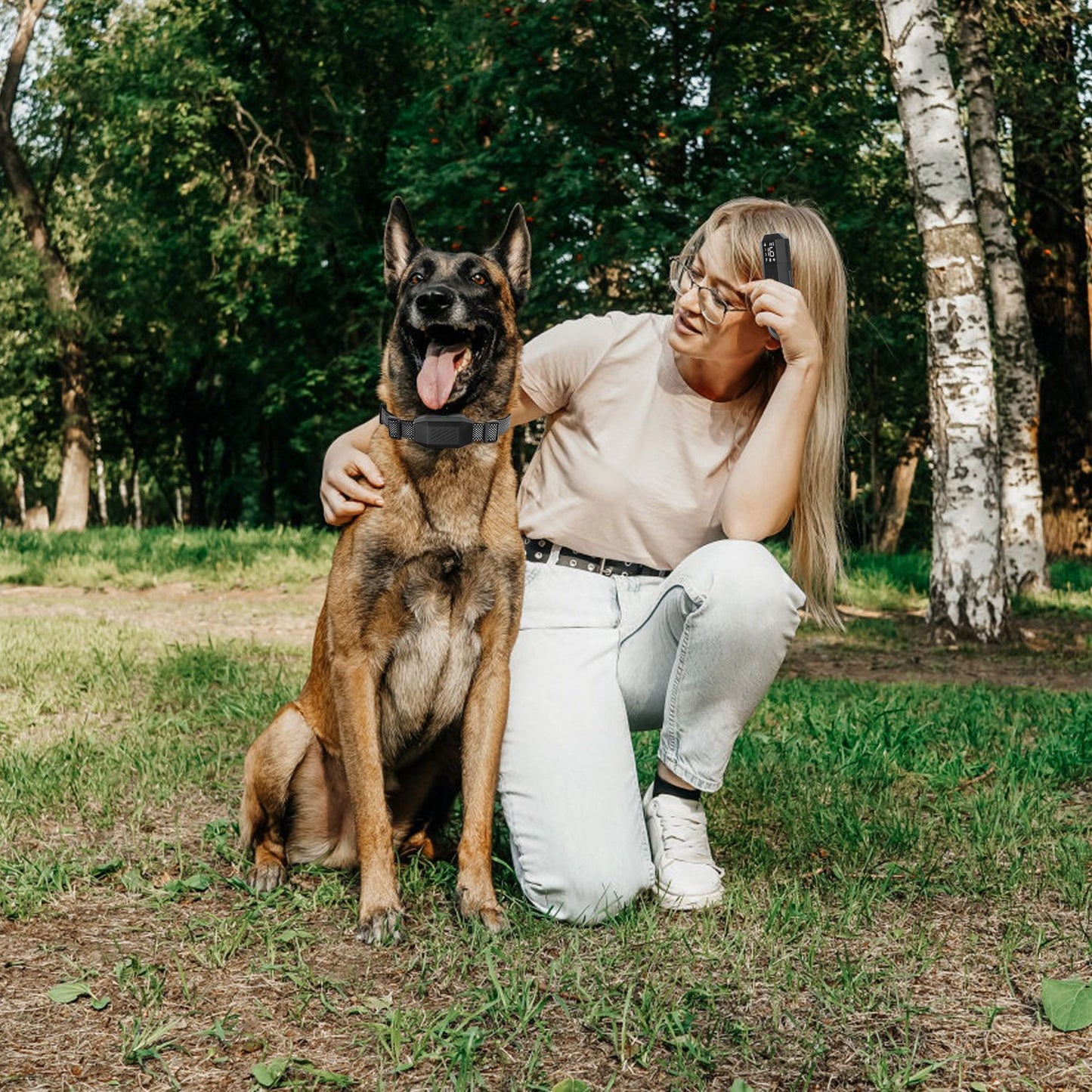 Person outdoors with large German shepherd wearing training collar while holding the transmitter