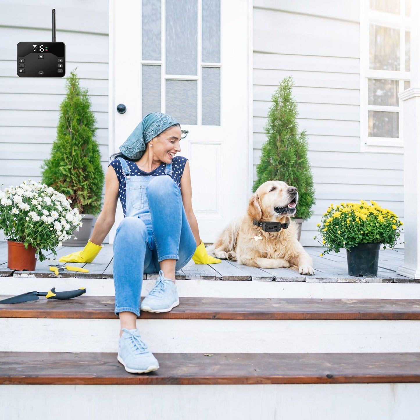 person sitting on porch with dog wearing receiver collar and transmitter shown mounted on house wall