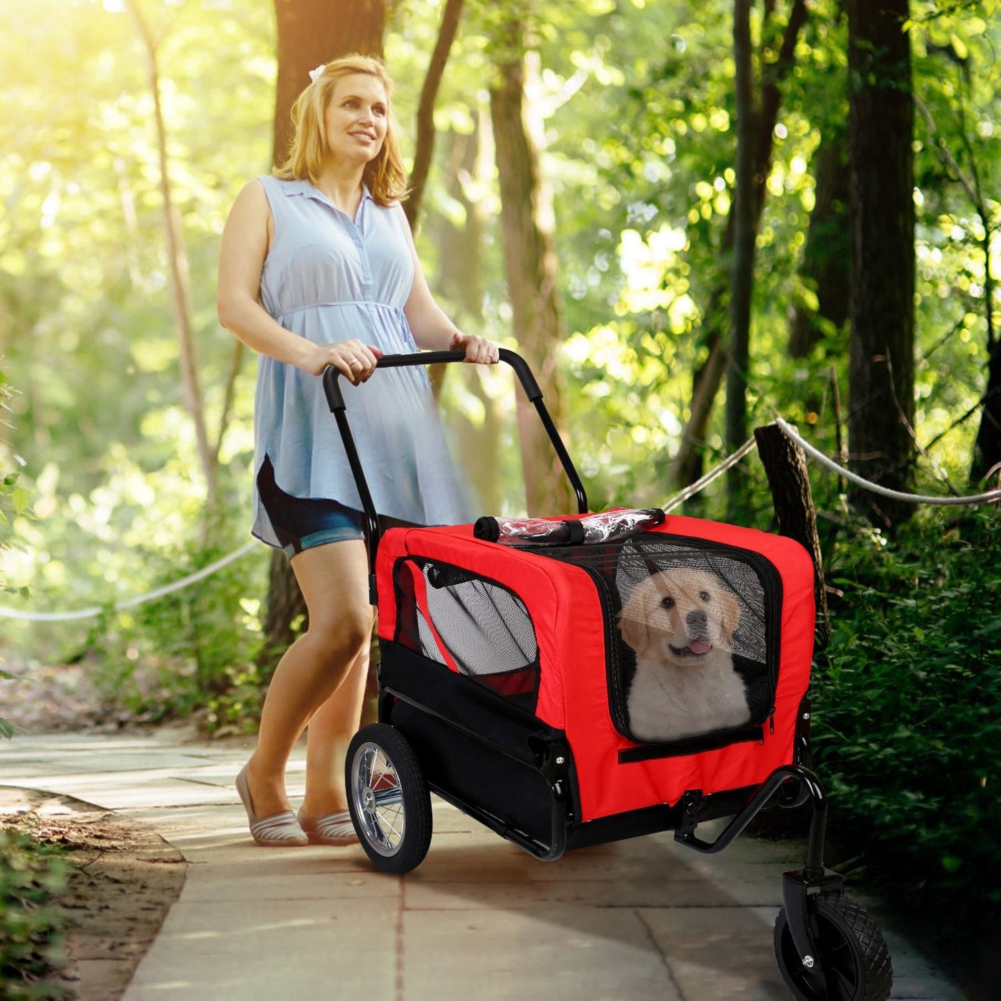 Person walking on a wooded path pushing red pet stroller with a small dog inside