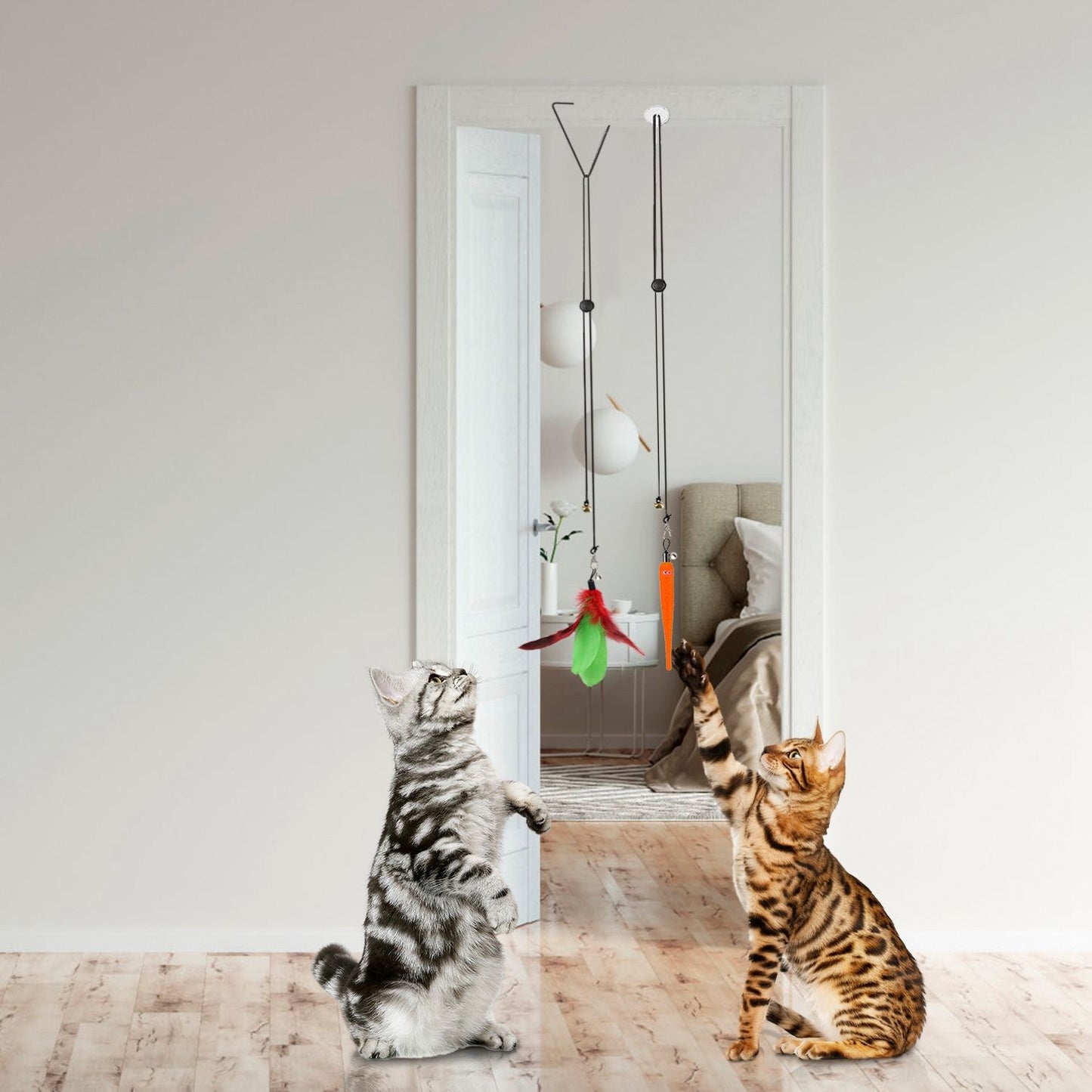 Two cats reaching up to hanging feather and worm toys suspended from a doorway clip and suction-mounted line