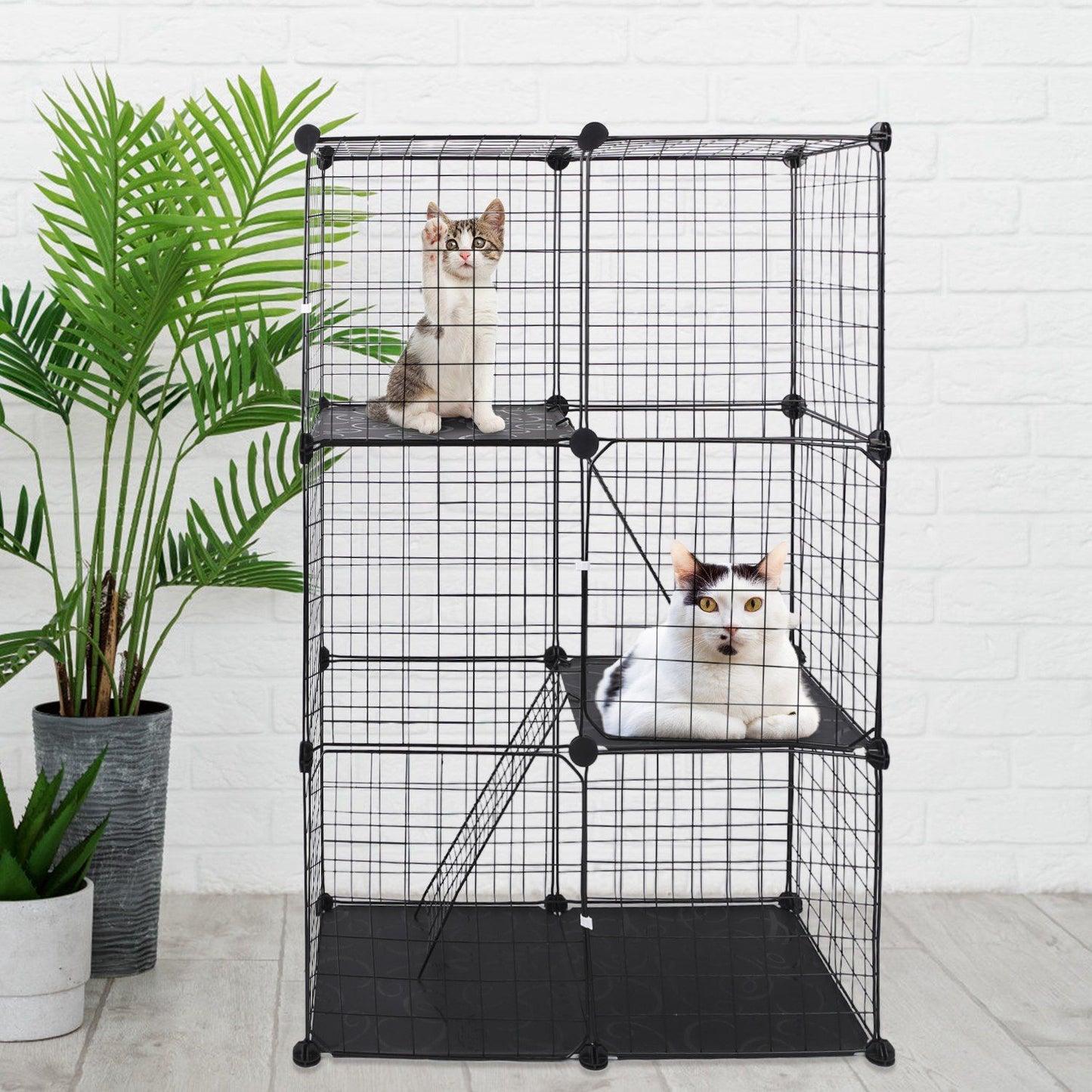 Three-tier black cat cage staged with plants and cats resting on platform perches