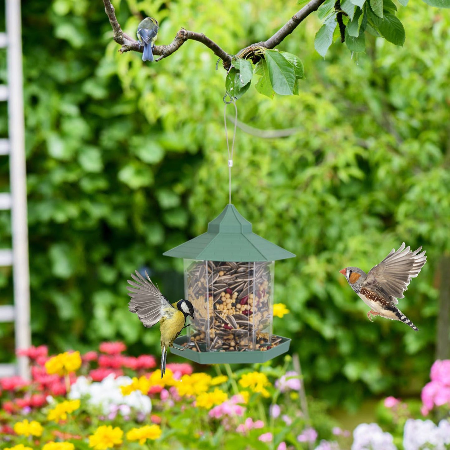 Green gazebo feeder hanging in a flower garden with birds feeding from clear seed ports