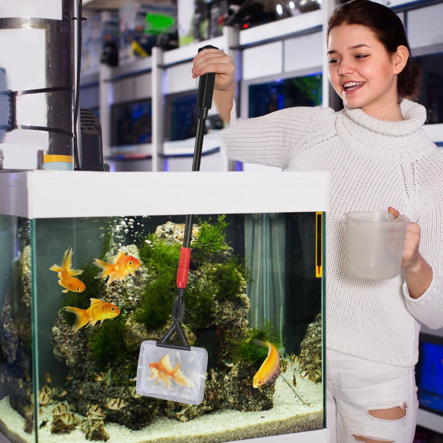 Person using the extendable handle and fish net to scoop a goldfish from an aquarium