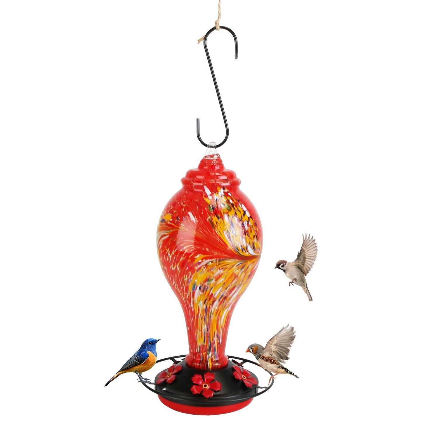 Red feeder hanging from a branch in front of a house with birds feeding below