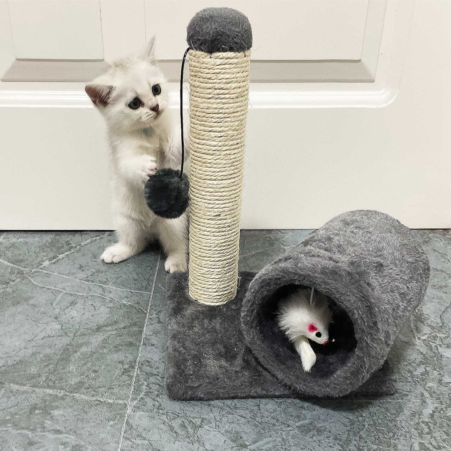 Small kitten batting dangling pom-pom on grey plush scratch post with tunnel mouse