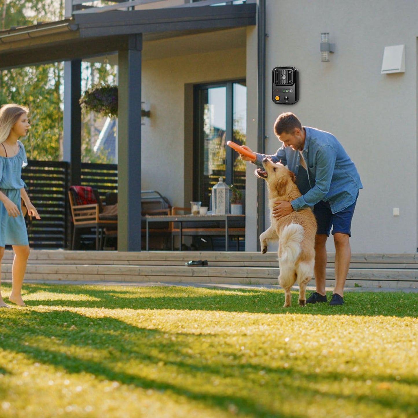 Man playing with dog in backyard with ultrasonic device mounted on exterior wall