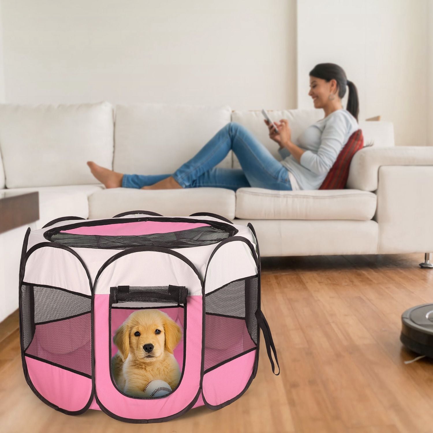Pink playpen on floor in living room with small puppy inside and person on sofa