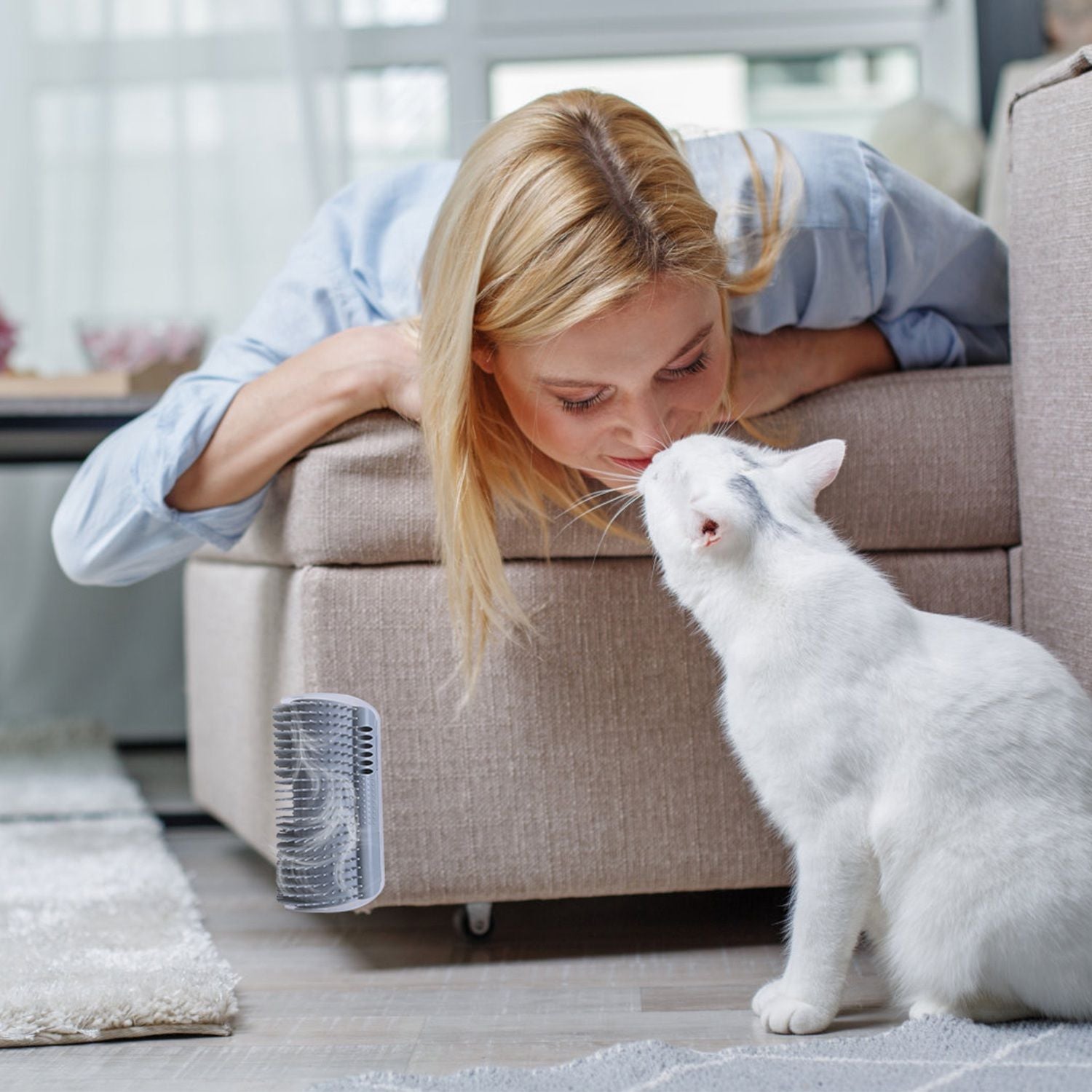White cat near a grey mounted groomer attached to the side of a sofa