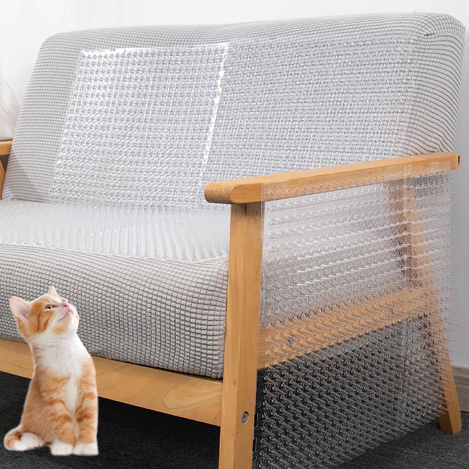 Transparent spiked mats placed over a sofa seat and armrest with a kitten nearby