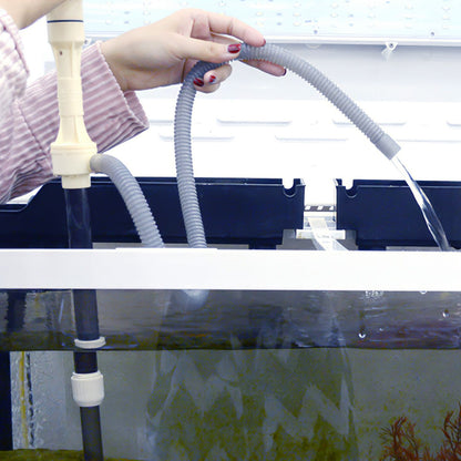 Flexible water hose discharging aquarium water into a container during cleaning