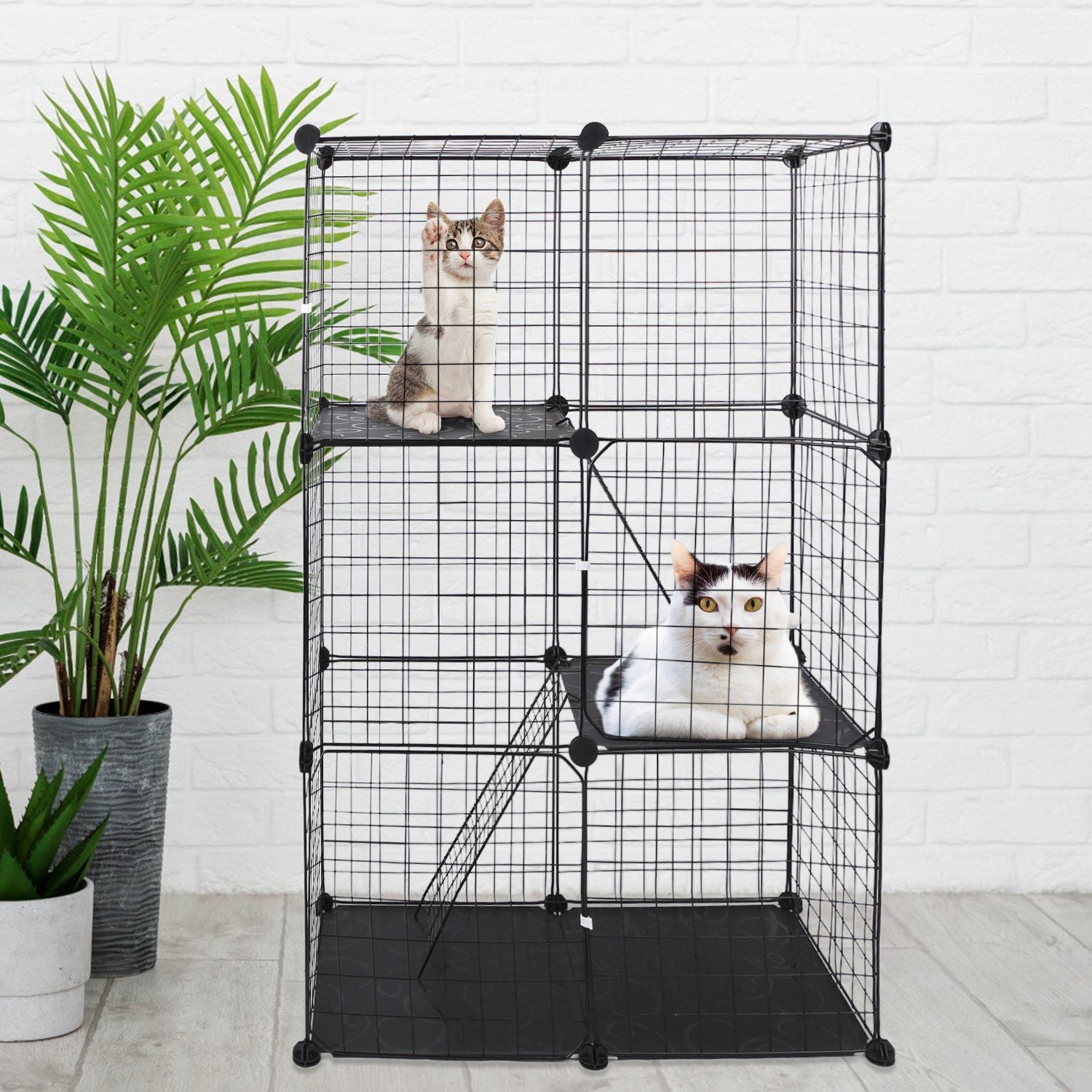 Three-tier black cat cage staged with plants and cats resting on platform perches
