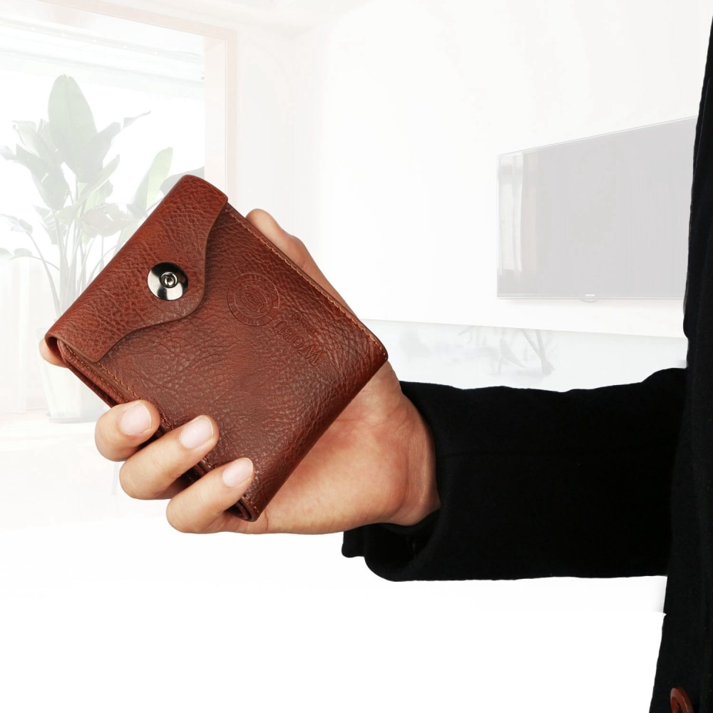 Brown leather wallet held in a hand, showcasing its textured surface and snap closure, with a modern interior setting in the background.