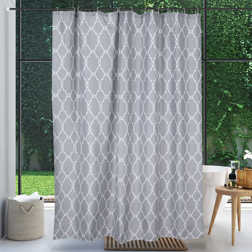 Stylish gray shower curtain with an elegant white geometric pattern, hanging in a modern bathroom with greenery visible through large windows.
