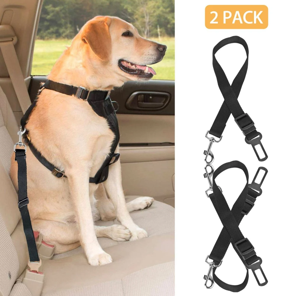 A happy Labrador retriever seated in a car wearing a black dog seat harness, next to a 2-pack of adjustable pet safety belts for car travel.