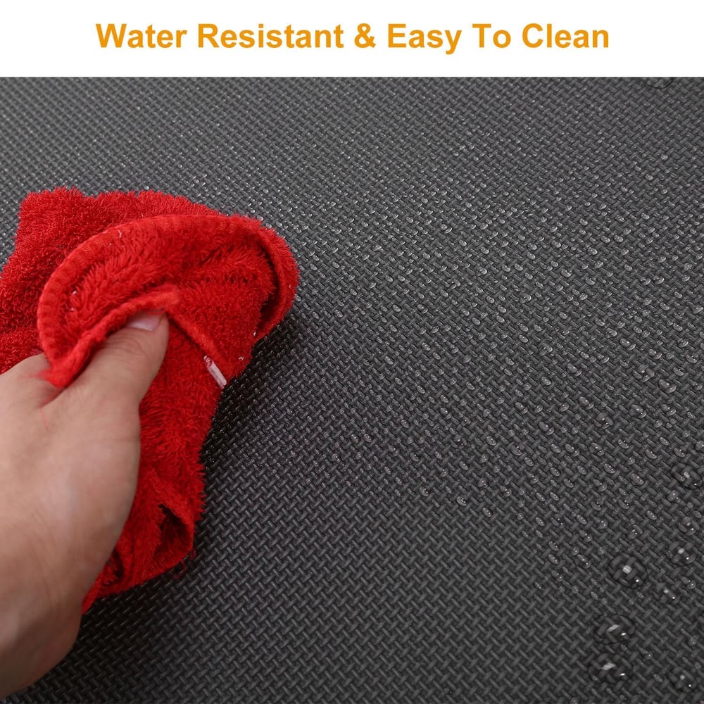 A person using a red cloth to wipe a textured black water-resistant surface, showcasing its easy-to-clean features.