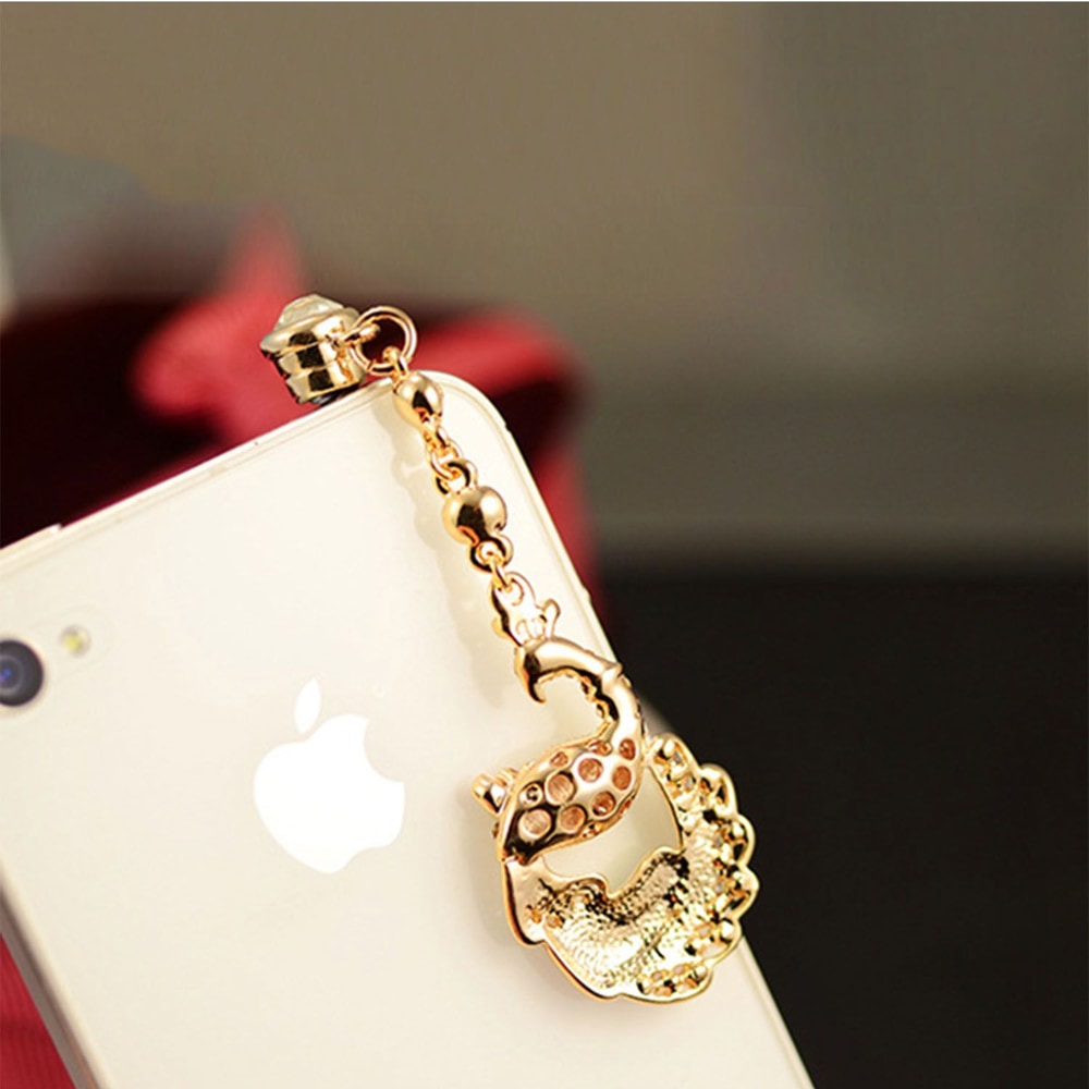 Decorative gold phone charm featuring a fish design, attached to a smartphone, enhancing its style and personal touch.