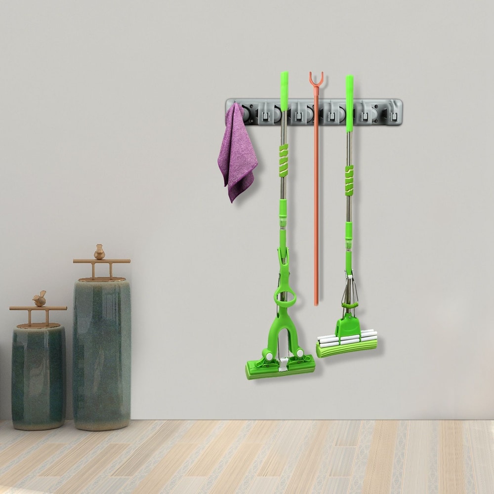 Wall-mounted storage rack displaying green cleaning tools, including mops and a cloth, organized neatly in a modern home setting.