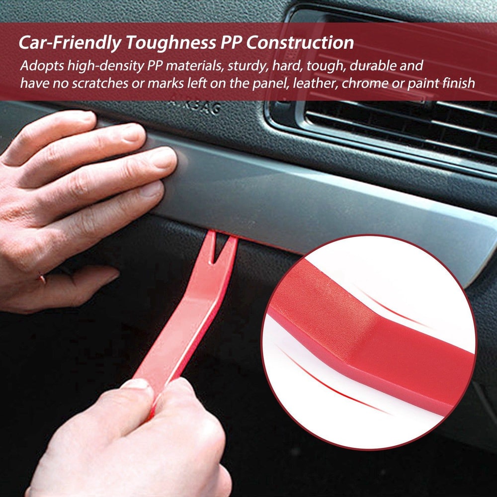 Red plastic automotive trim removal tool being used on a car panel, designed to prevent scratches and damage while working on interior trim.