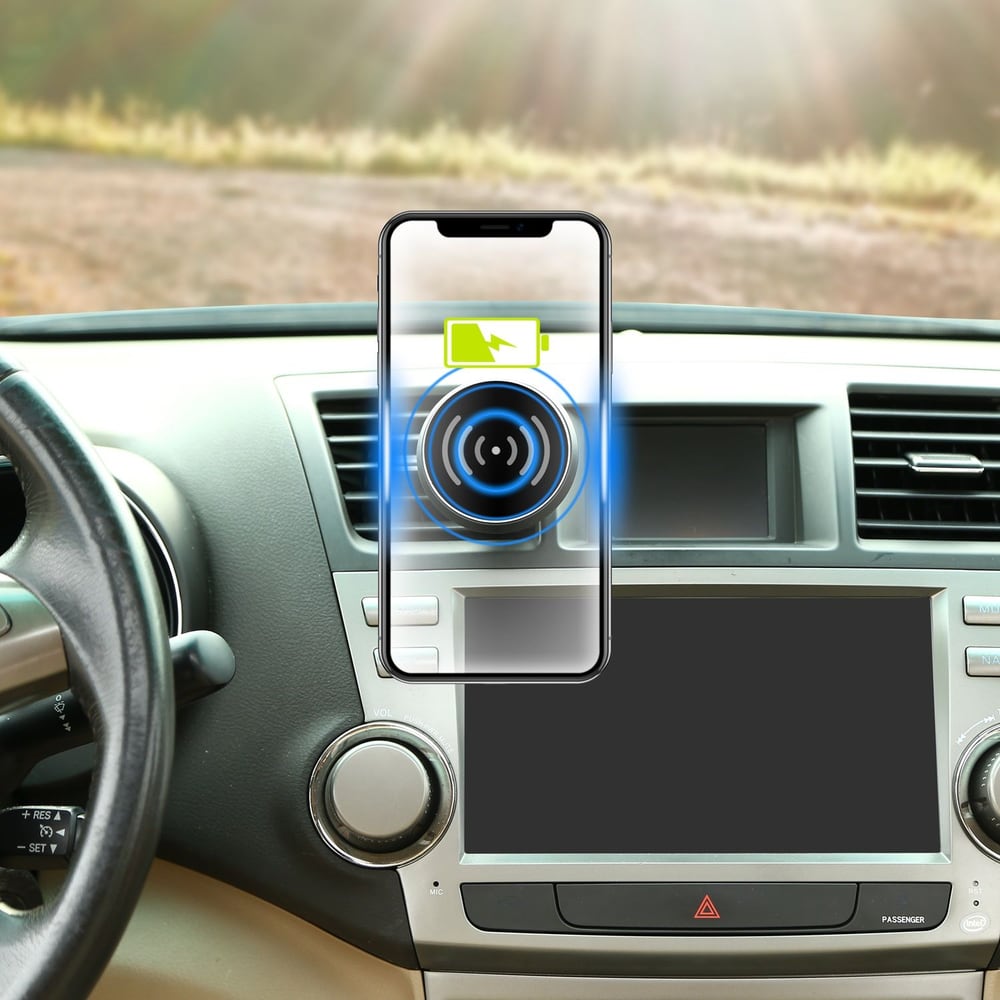 Smartphone wirelessly charging on car dashboard, displaying battery icon and charging symbol, with sunlight streaming in the background.