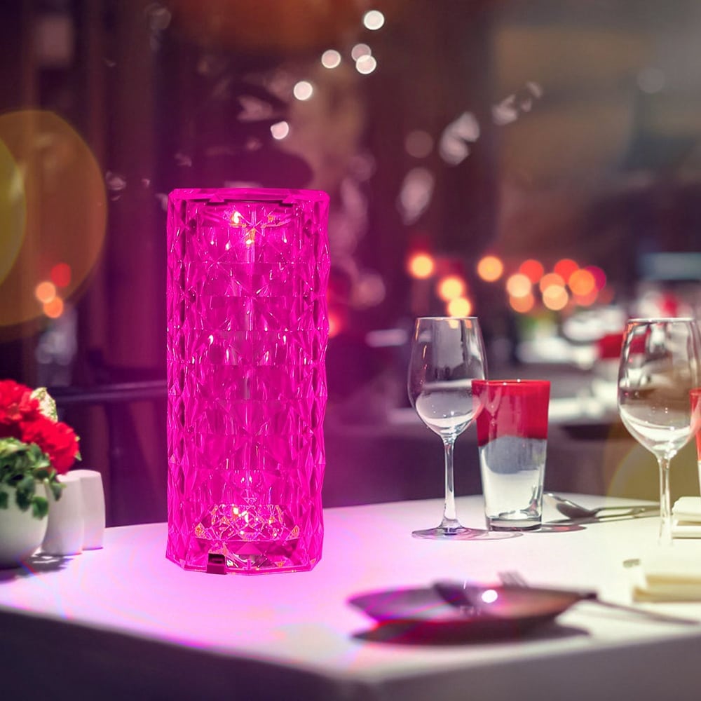 Elegant pink geometric table lamp casting a warm glow on a dining table, surrounded by wine glasses and soft candlelight, perfect for creating an intimate atmosphere.