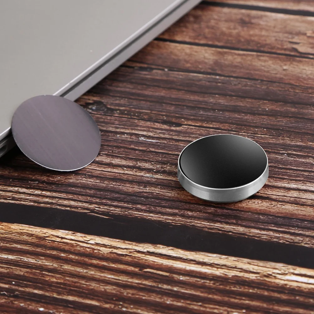 Black and silver magnetic phone mount discs on a wooden surface, designed for secure phone attachment to any flat surface.