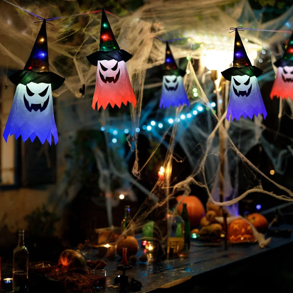 Colorful Halloween ghost lanterns with witch hats hanging in a spooky setting adorned with spider webs, pumpkins, and candles.