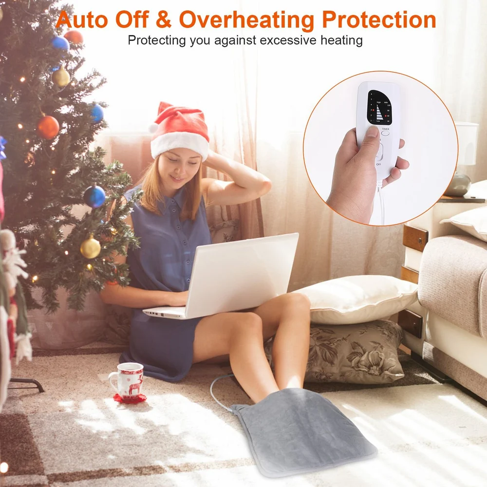 A woman sitting by a Christmas tree in a cozy living room, using a laptop with a heating pad under her feet, featuring an auto-off and overheating protection controller in her hand.