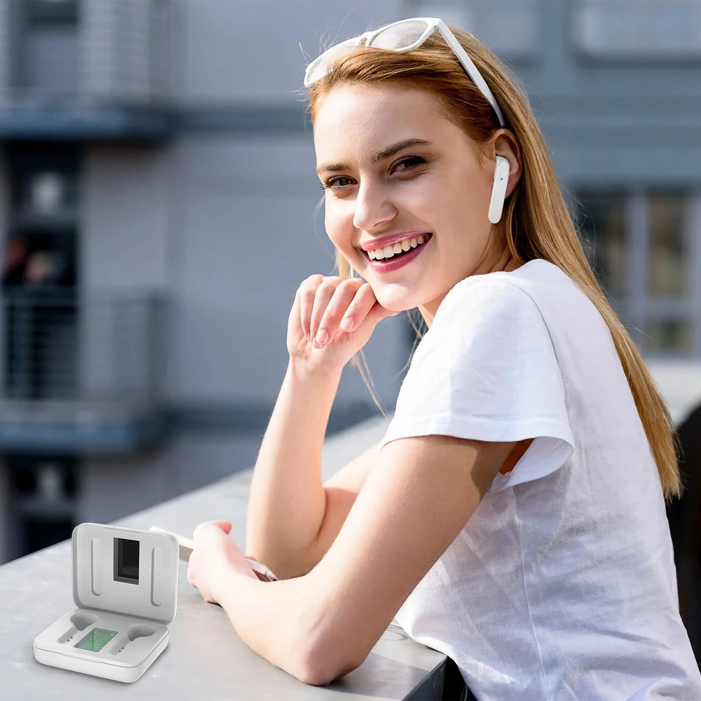 Young woman wearing wireless earbuds, casually resting her chin on her hand while sitting by a railing, with a white open charging case displaying earbuds in the foreground, amidst a modern urban backdrop.