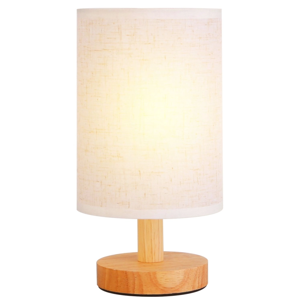 Modern table lamp with a cylindrical fabric shade and a natural wooden base, emitting a soft warm light, perfect for cozy home decor.