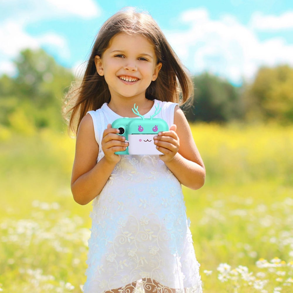 Child holding a colorful, kawaii-style camera in a sunny field with vibrant green grass and wildflowers.