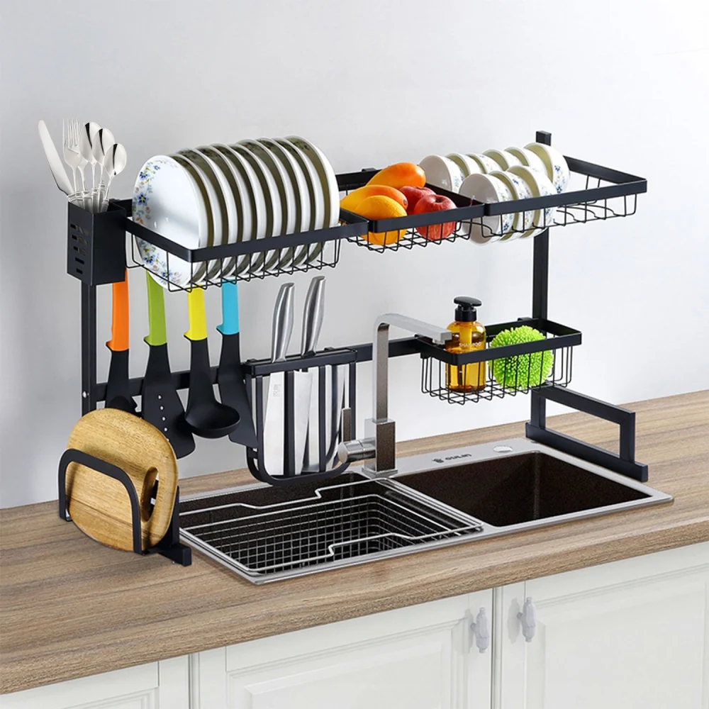 Multi-tier kitchen sink organizer with drying rack, plates, fruits, utensils, and dishware displayed on a wooden countertop.