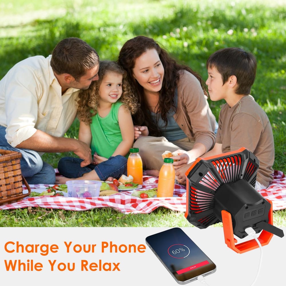 Portable phone charger and mini fan on a picnic blanket with family enjoying drinks outdoors, showcasing the convenience of charging devices while relaxing.