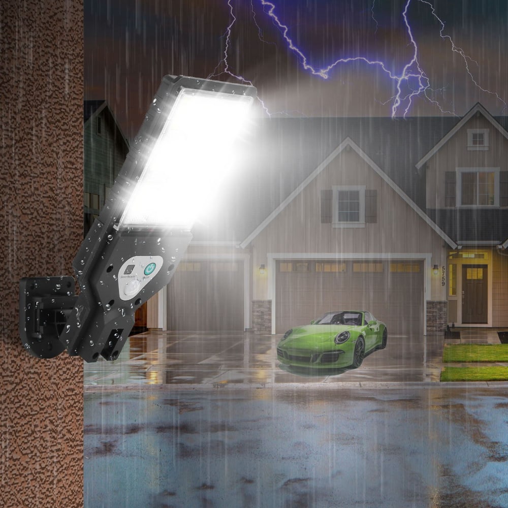 Bright LED outdoor floodlight mounted on a textured wall, illuminating a rainy evening scene with a modern home and a vibrant green sports car in the driveway.