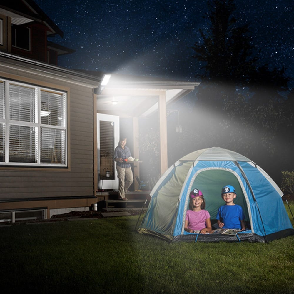 Family camping night in the backyard with a tent, two children inside, and an adult on the porch, under a starry sky illuminated by a light, promoting outdoor fun and adventure.