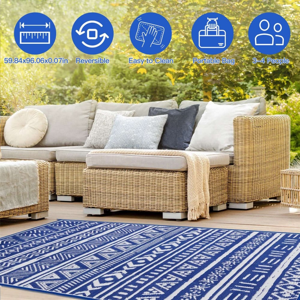 Reversible outdoor rug in blue and white geometric pattern, measuring 59.84x96.06 inches, easy to clean, portable with a carrying bag, suitable for 3-4 people, showcased on a patio with a wicker sofa and decorative cushions.