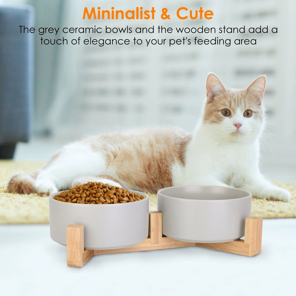 Minimalist grey ceramic pet bowls on a wooden stand with cat in the background, perfect for stylish pet feeding areas.