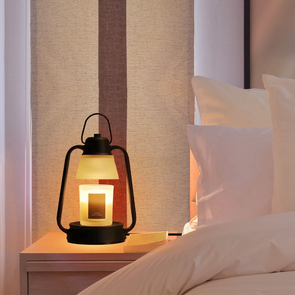 Stylish bedside lamp with candlelight, black metal frame, and warm glow, set against a softly lit bedroom with neutral tones and soft bedding.